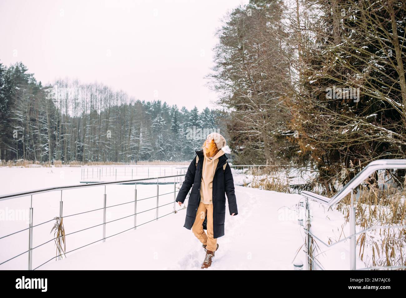 Mujer joven con estilo vistiendo ropa de abrigo tocando la nieve y