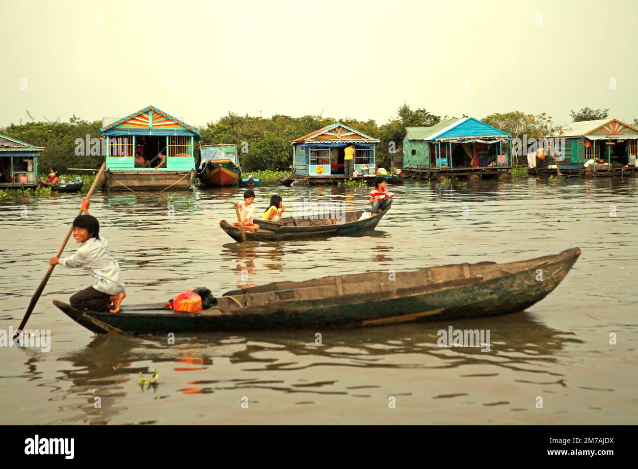 Niños viajando en barcos en un fondo de casas flotantes de un pueblo flotante en Tonle Sap, el lago de agua dulce más grande de Camboya, en esta foto de 2013. Desde al menos noviembre de 2021, las autoridades camboyanas han estado tratando de proteger más estrechamente los recursos naturales de la zona, incluidos los santuarios de peces, según informó el Phnom Penh Post el 3 de enero de 2023. Los delitos pesqueros en la zona se reprimirán de nuevo en 2023, tras las exitosas campañas que llevaron a un aumento de la producción pesquera el año pasado. Foto de stock