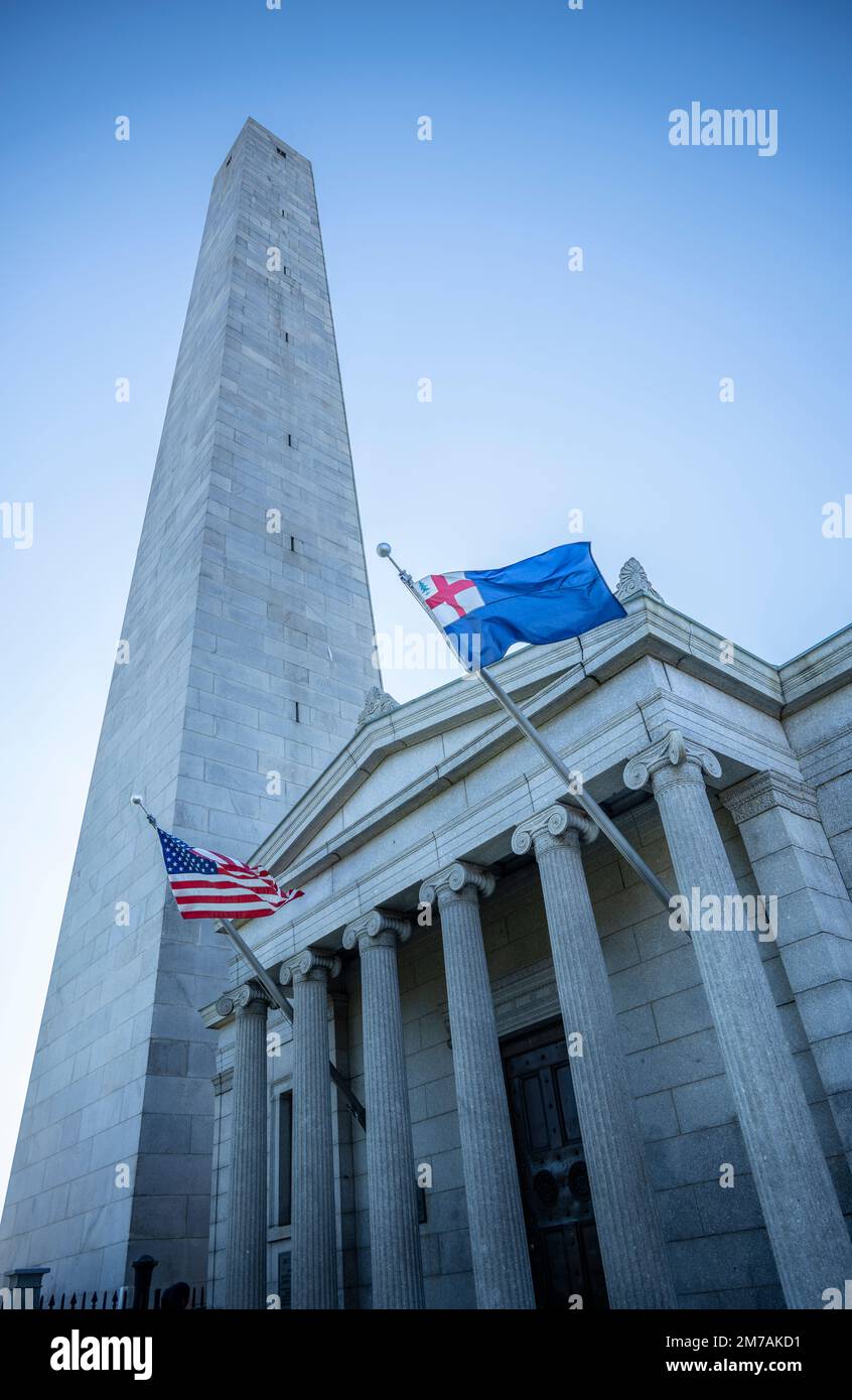 Bunker Hill Monument en Charlestown con obelisco y albergue junto con la bandera de los Estados Unidos y la bandera de Nueva Inglaterra ondeados en el campo de batalla en Breed's Hill Foto de stock