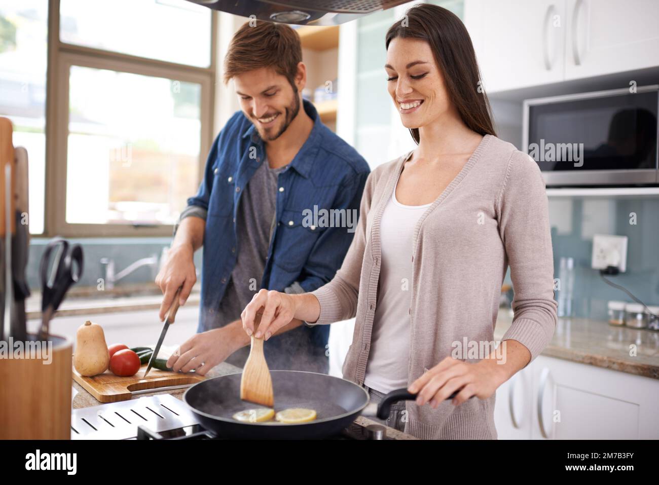 Preparar una deliciosa comida en casa. Una pareja joven haciendo la cena juntos en casa. Foto de stock