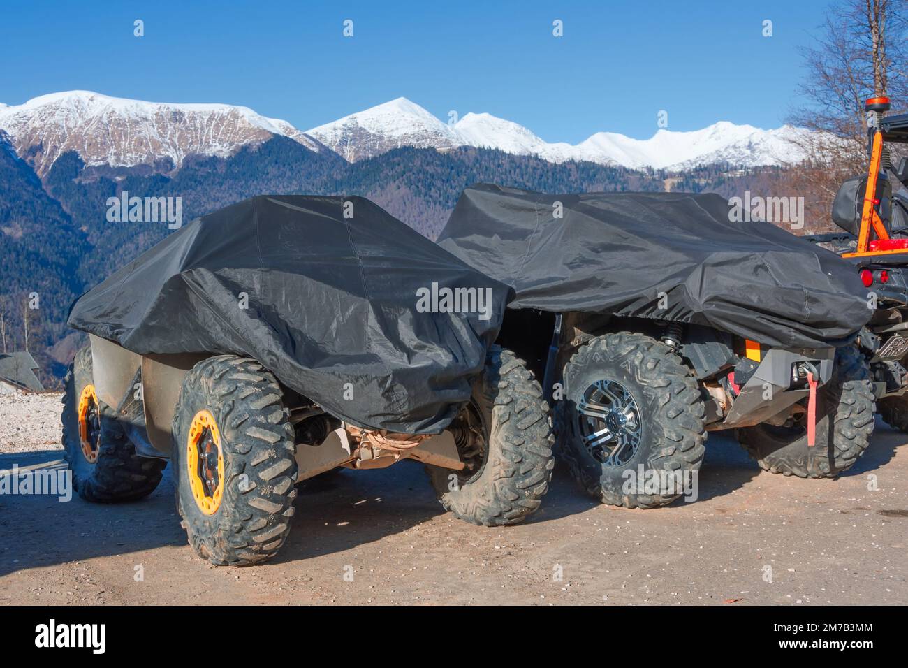 El refugio con una cubierta protectora con una lona de vehículos todoterreno se coloca contra el telón de fondo de las montañas cubiertas de nieve Foto de stock