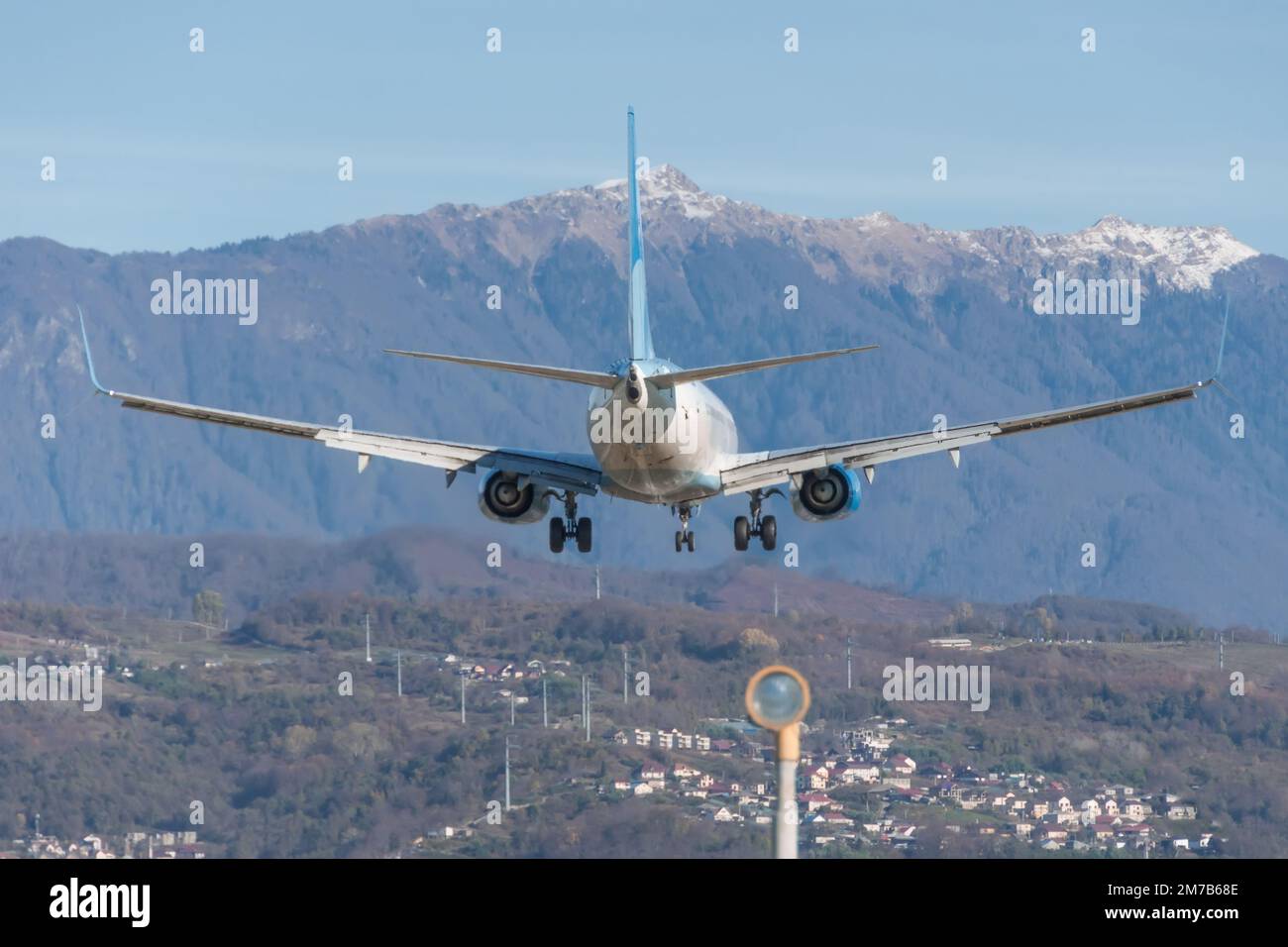 Avión de pasajeros aterrizó en el aeródromo en las montañas, en la distancia de un pueblo en una pendiente Foto de stock