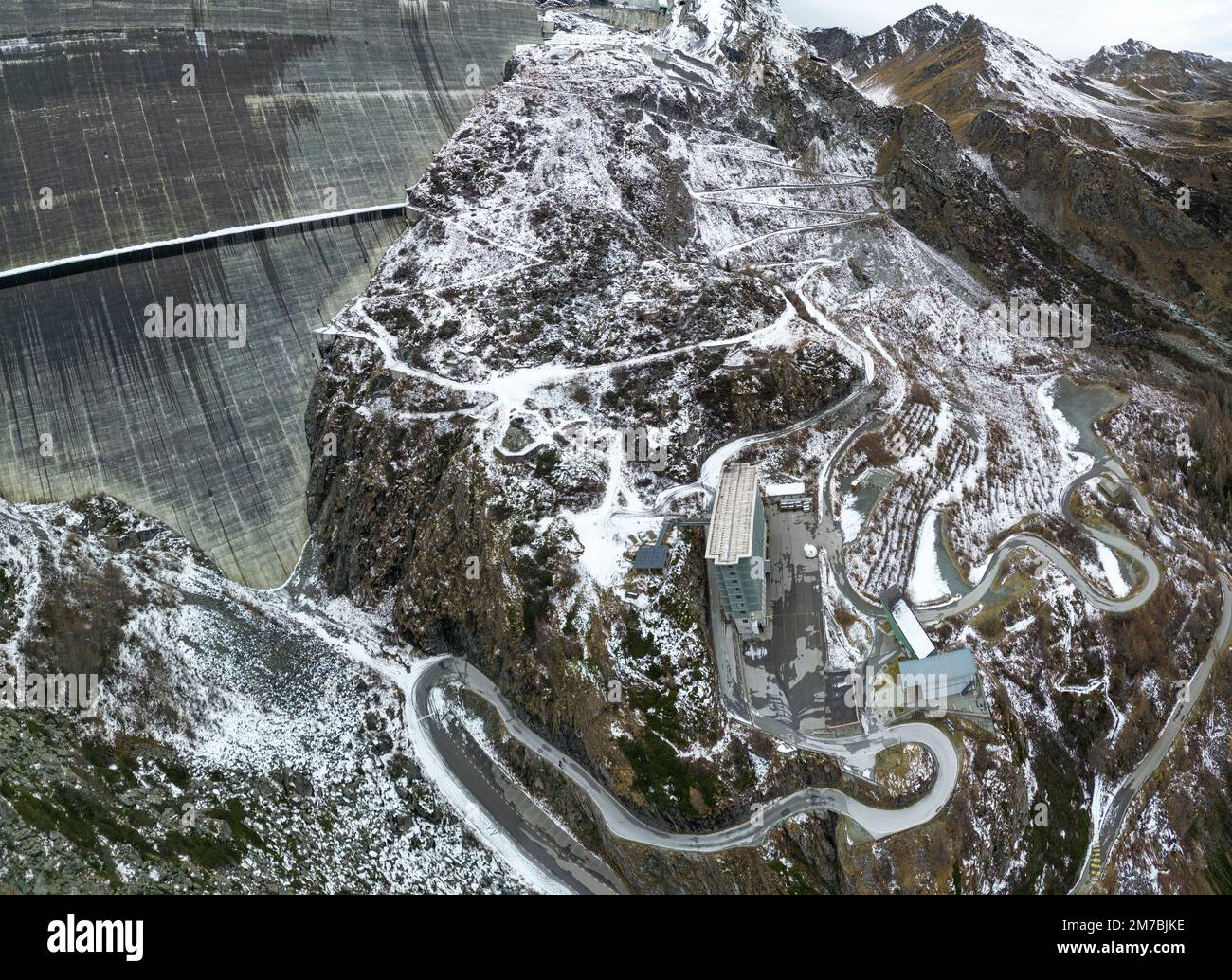 Impresionantes imágenes de drones sobre un lago alpino, una presa hidroeléctrica y un vasto embalse alpino bordeado por montañas escarpadas con un sendero junto al agua después de la primera nieve Foto de stock