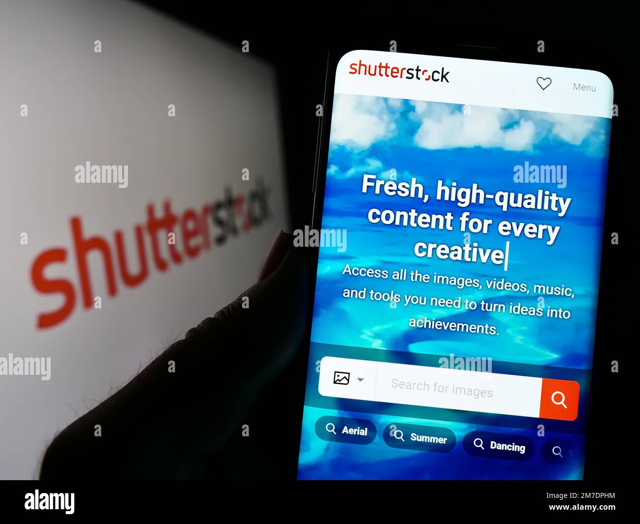 Persona que sostiene el teléfono móvil con el sitio web de la compañía de fotografía de stock de EE.UU. Shutterstock Inc. En la pantalla con el logotipo. Enfoque en el centro de la pantalla del teléfono. Foto de stock