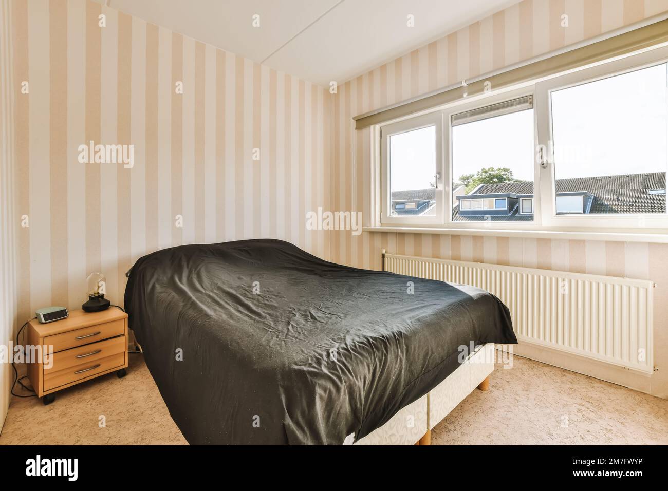 un dormitorio con empapelado a rayas en las paredes y una cama negra en la  cabecera de la habitación Fotografía de stock - Alamy