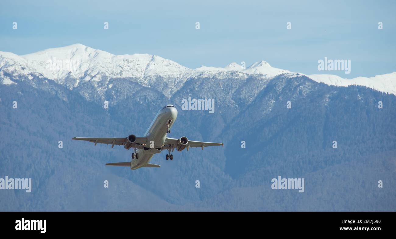 Los aviones civiles de pasajeros despegan con el telón de fondo de enormes montañas cubiertas de nieve Foto de stock