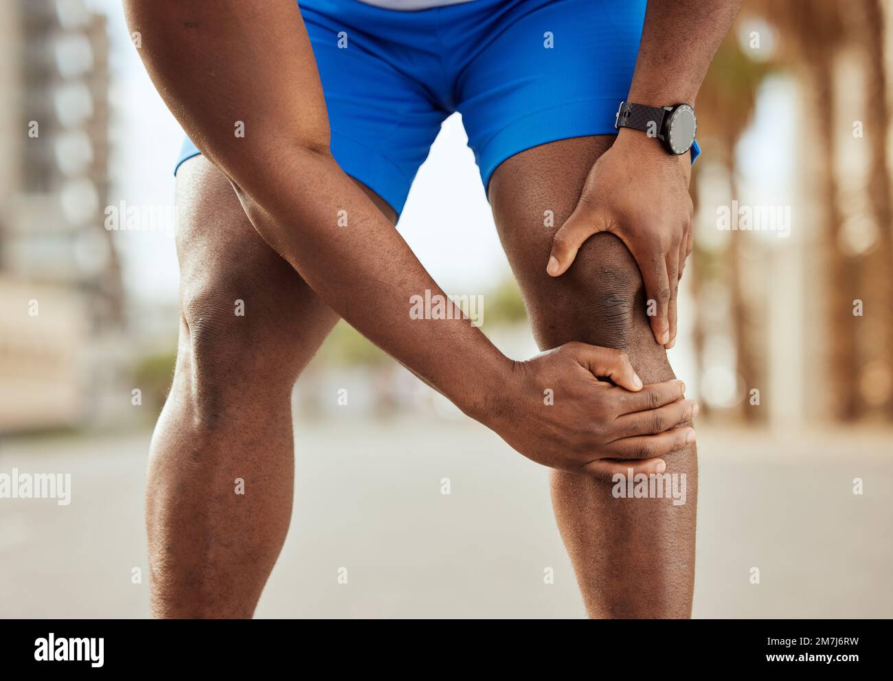 Fitness, dolor en la rodilla y las manos del hombre negro con dolor muscular,  dolor articular y lesión después de correr en la ciudad. Deportes,  bienestar corporal y atleta masculino Fotografía de