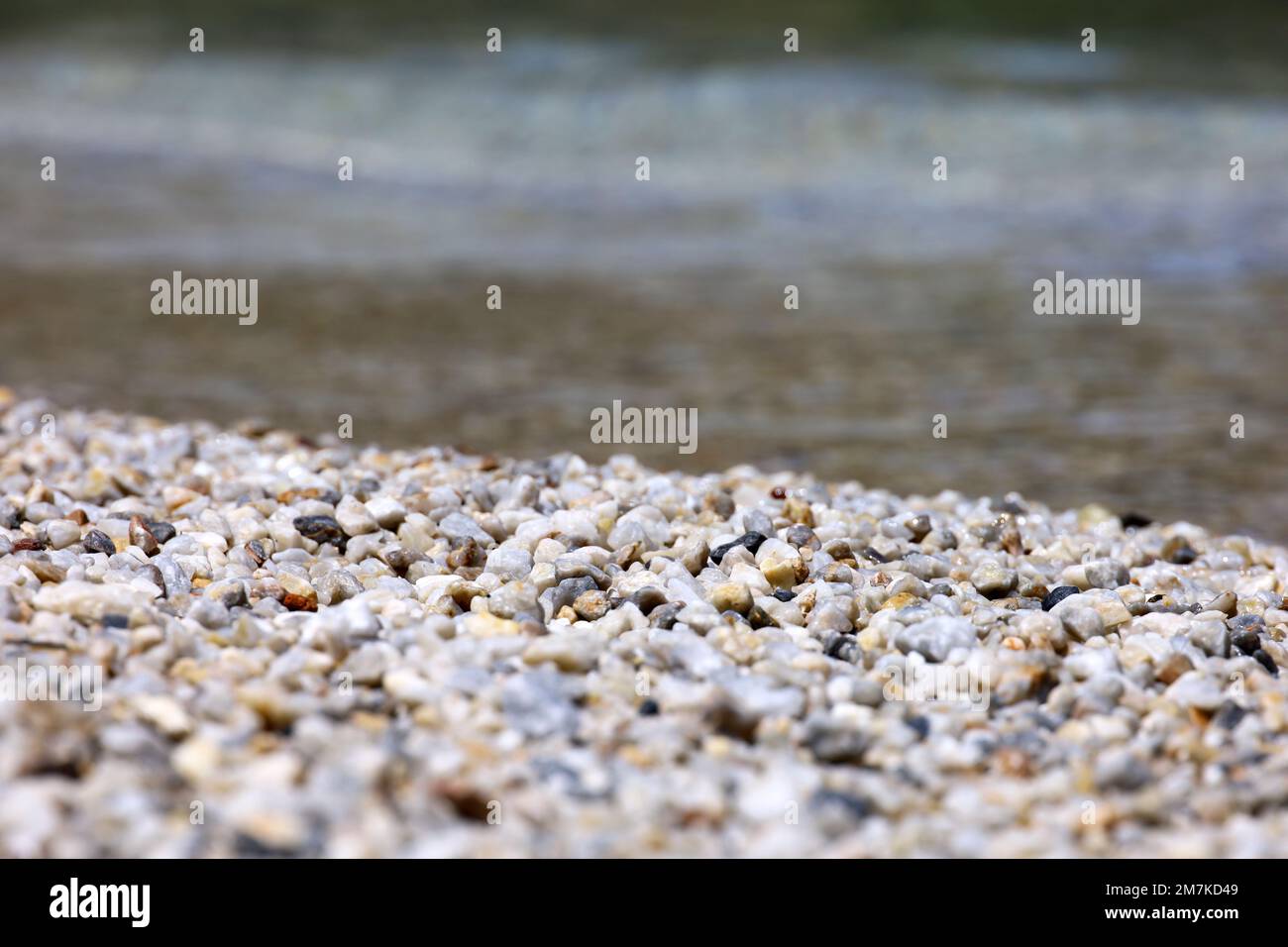 Pequeñas piedras de guijarros en la playa de mar con agua transparente. Fondo natural para las vacaciones de verano Foto de stock