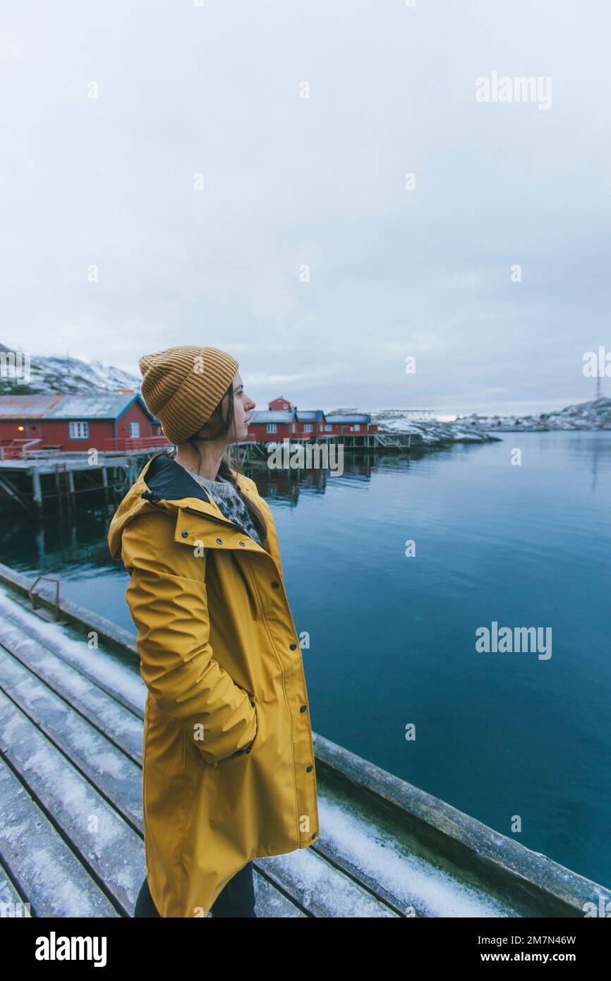 Mujer joven con impermeable amarillo en Noruega, Lofoten, pueblo de pescadores Foto de stock