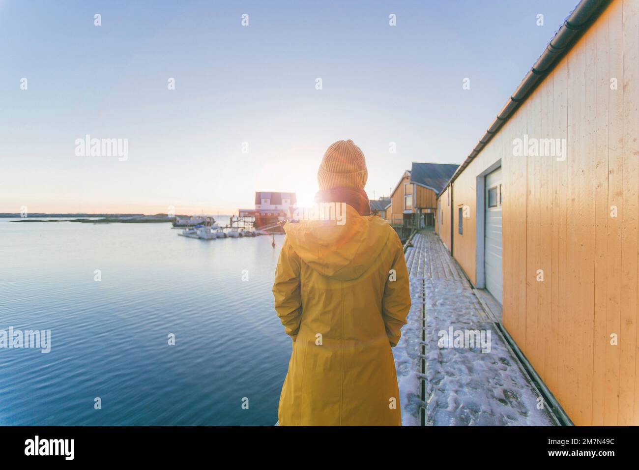 Mujer joven con impermeable amarillo en Noruega, Lofoten, pueblo de pescadores Foto de stock