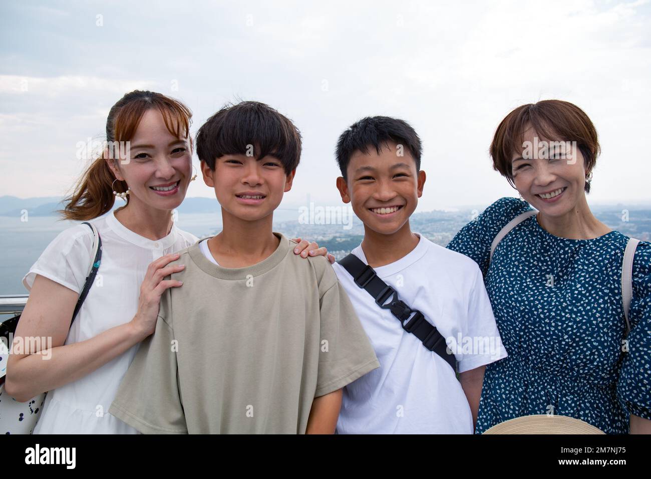 Cuatro japoneses en una excursión, dos mujeres maduras y dos niños de 13 años, en una fila, en una plataforma de observación. Foto de stock