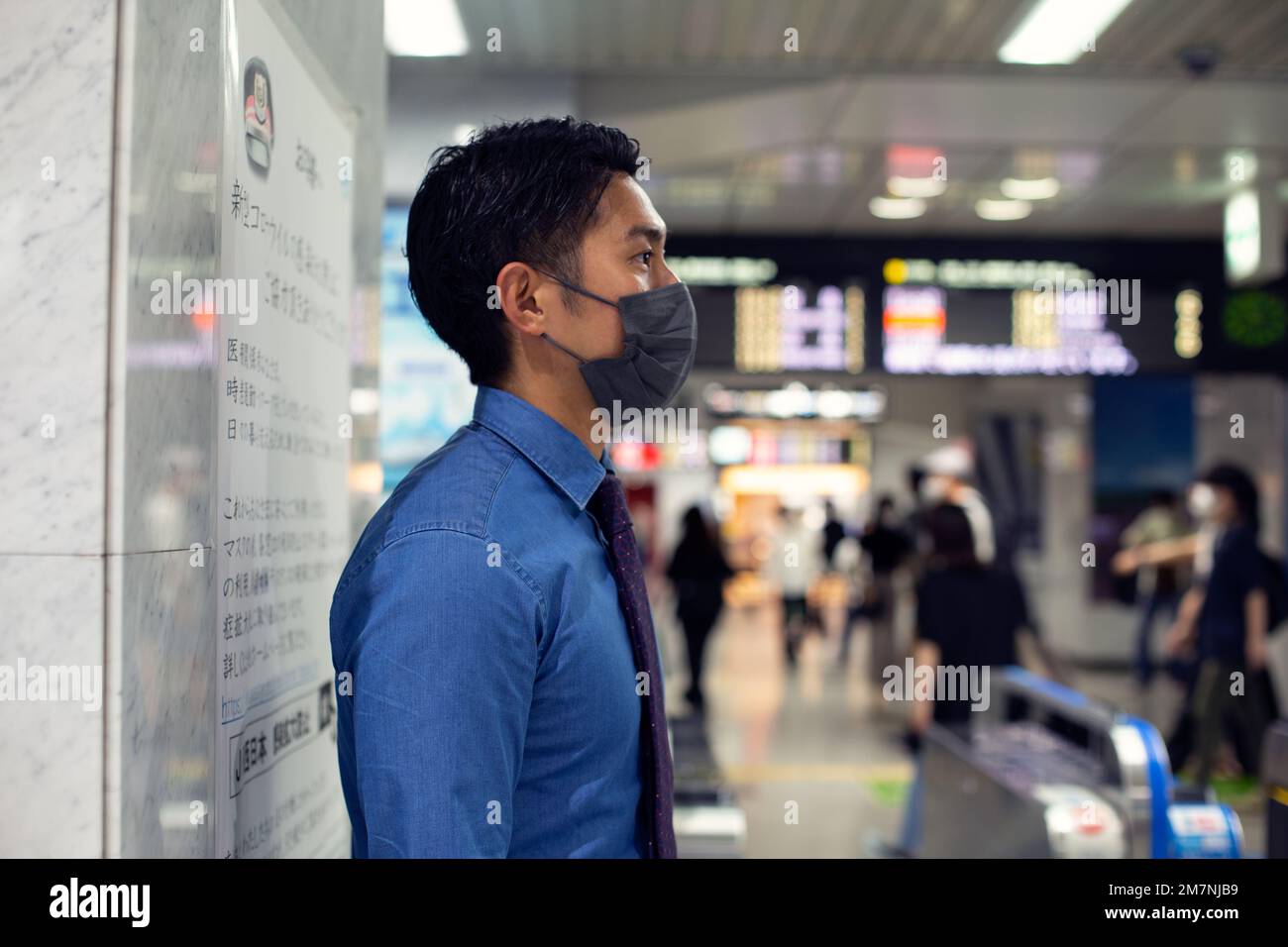 Un joven hombre de negocios en la ciudad, en movimiento, de pie en una estación de metro, con una máscara facial. Foto de stock