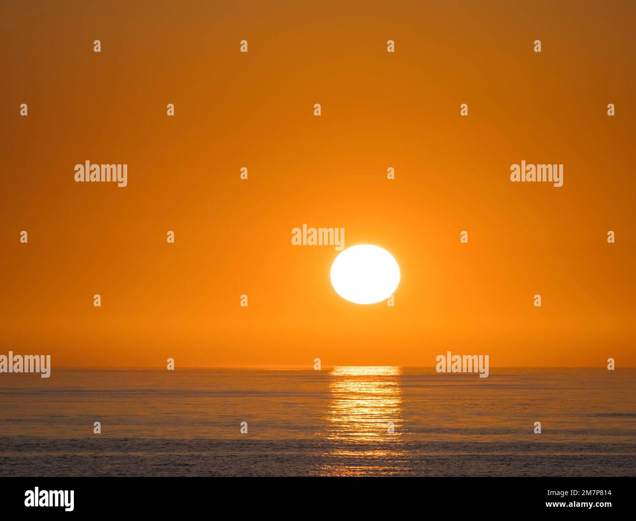 Sol a punto de ponerse en un cielo naranja vacío justo por encima del horizonte sobre el Golfo de México Foto de stock