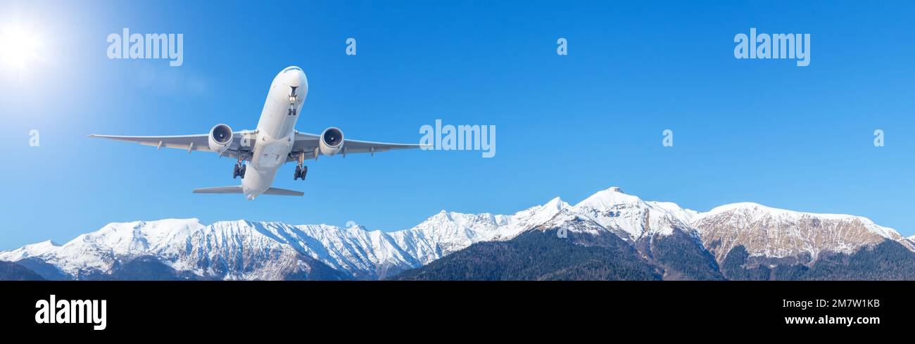 Avión de pasajeros de avión grande despega rápidamente sobre una cadena montañosa contra el fondo con un cielo claro, bandera amplia vista Foto de stock