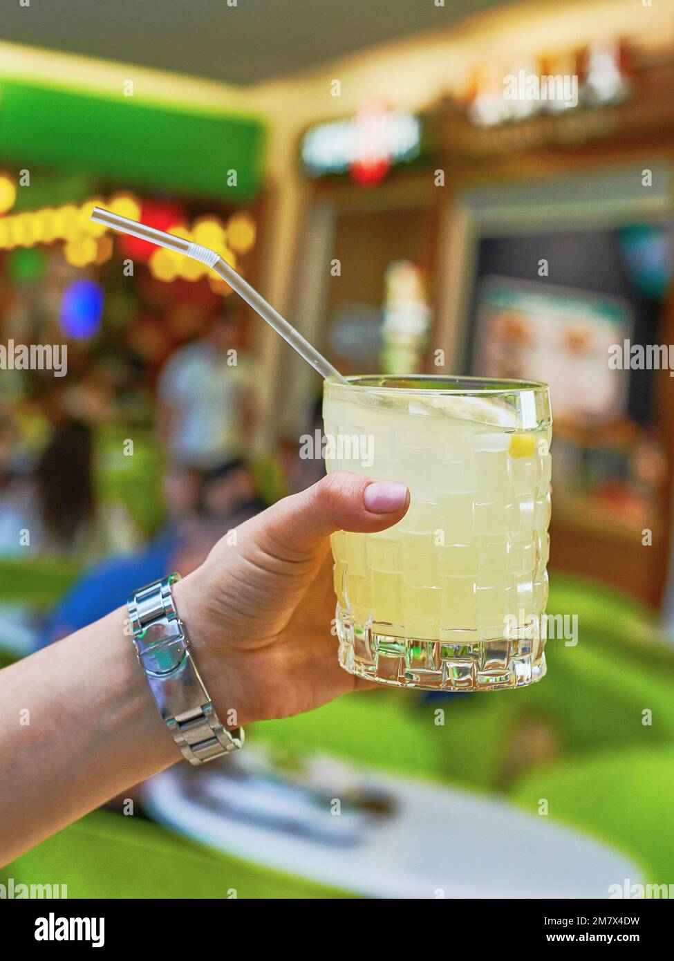 Cóctel de limonada amarilla a la mano en el fondo del restaurante con soda  y limón. Vista de primer plano Fotografía de stock - Alamy