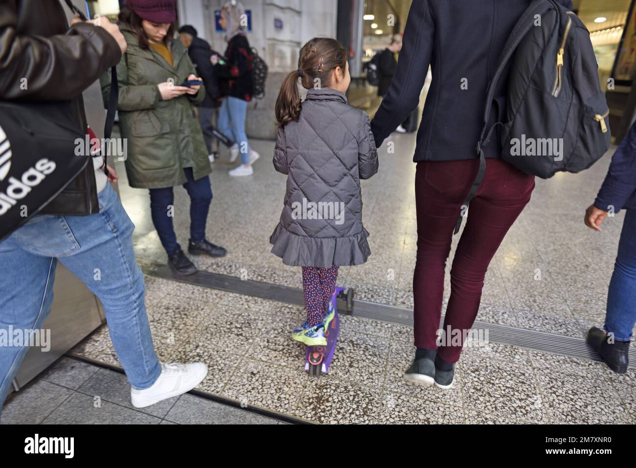 Londres, Inglaterra, Reino Unido. Chica joven con su madre y scooter púrpura - Victoria Station Foto de stock