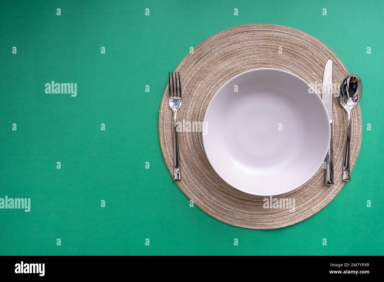 Comida, estilo ecológico, minimalista, comer y dieta concepto. Plato y utensilio de comedor en la alfombra de la mesa con fondo de color verde. El sol brilla a través Foto de stock