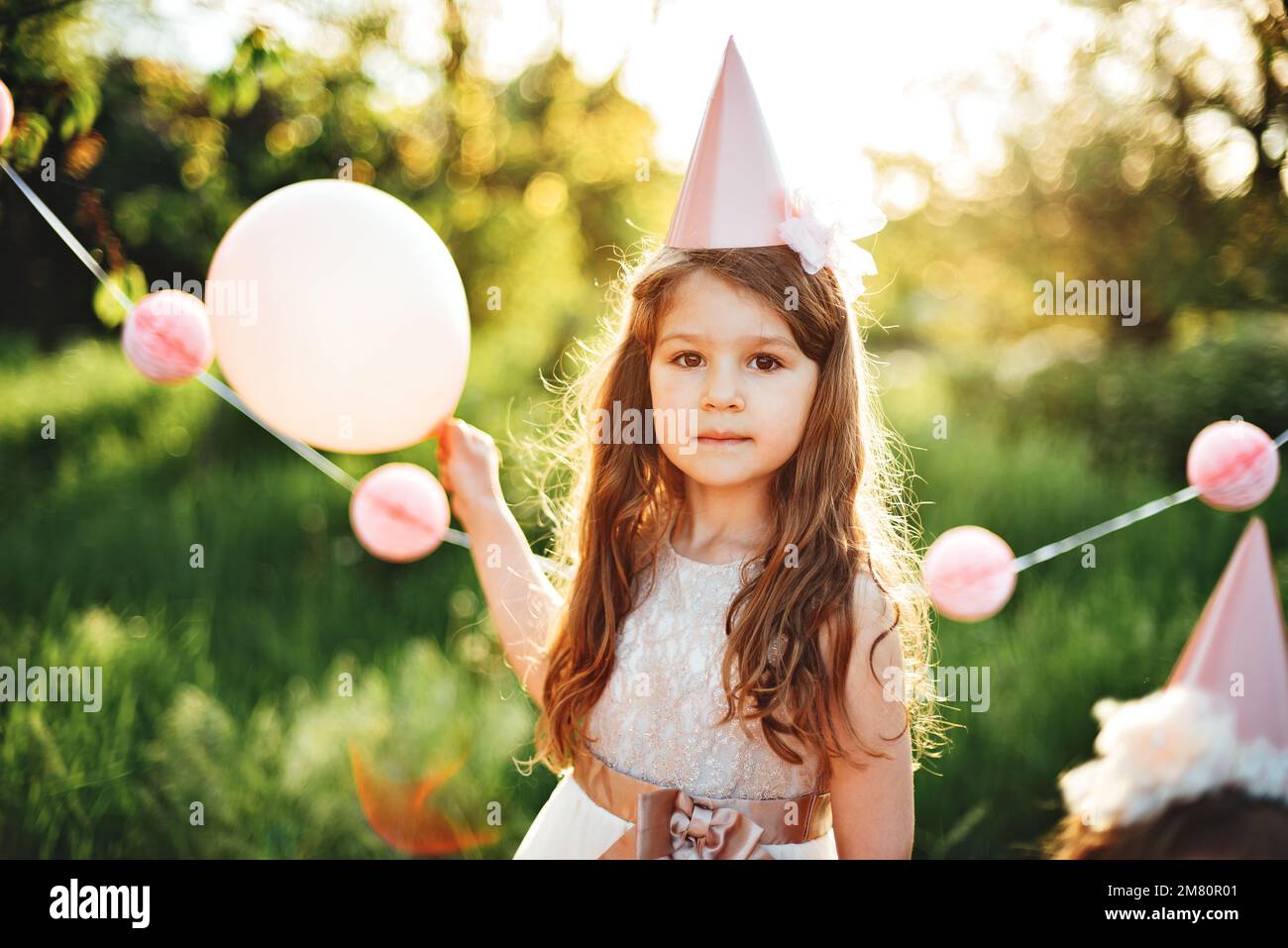 Niña feliz del cumpleaños con la caja de regalo en el hermoso jardín. niño  come feliz cumpleaños cupcake rosa. decoración colorida en tonos pastel al  aire libre. niño de 4 años celebrando