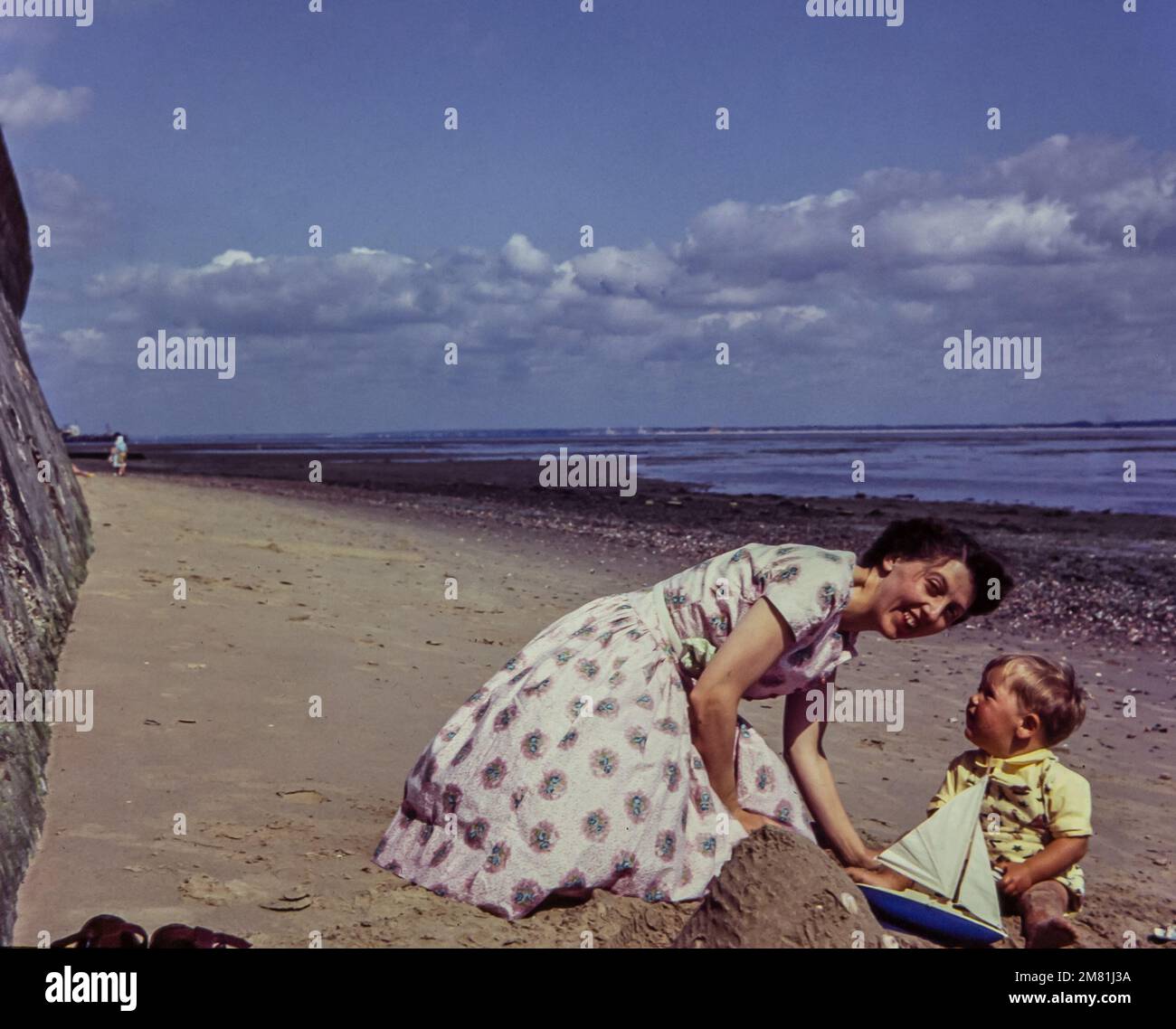Una joven madre a finales de los años 1950s en una playa con su hijo pequeño. Esta foto fue tomada de la diapositiva original. Foto de stock