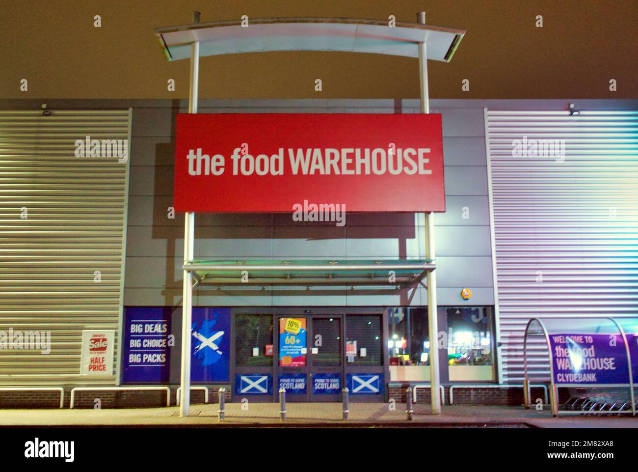 El cartel de la tienda del almacén de alimentos encima de la entrada principal por la noche sin gente Clyde Retail Park, Livingston Street, Clydebank Foto de stock
