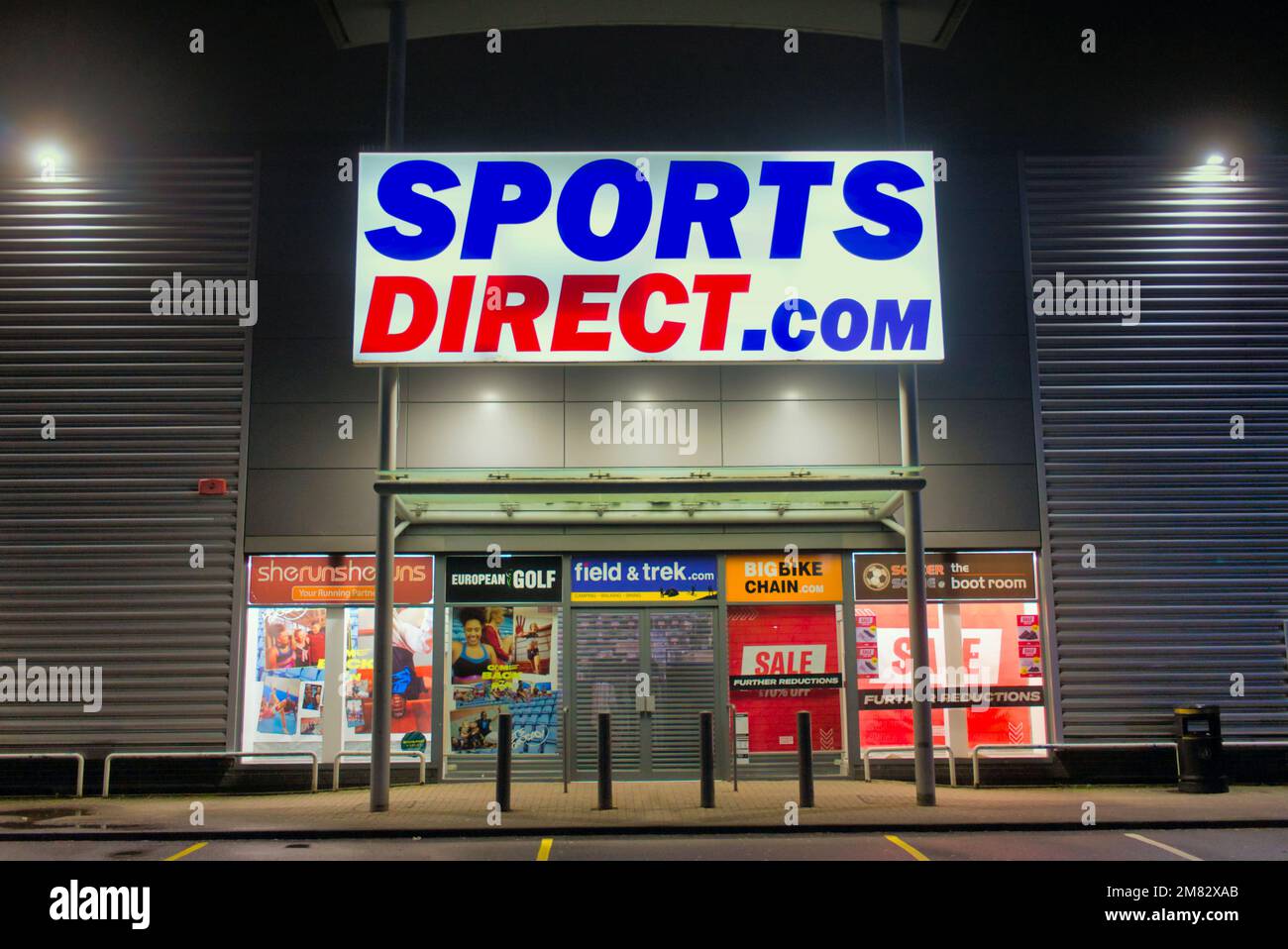 Cartel de tienda .com directo de deportes sobre la entrada principal por la noche sin personas Clyde Retail Park, Livingston Street, Clydebank Foto de stock