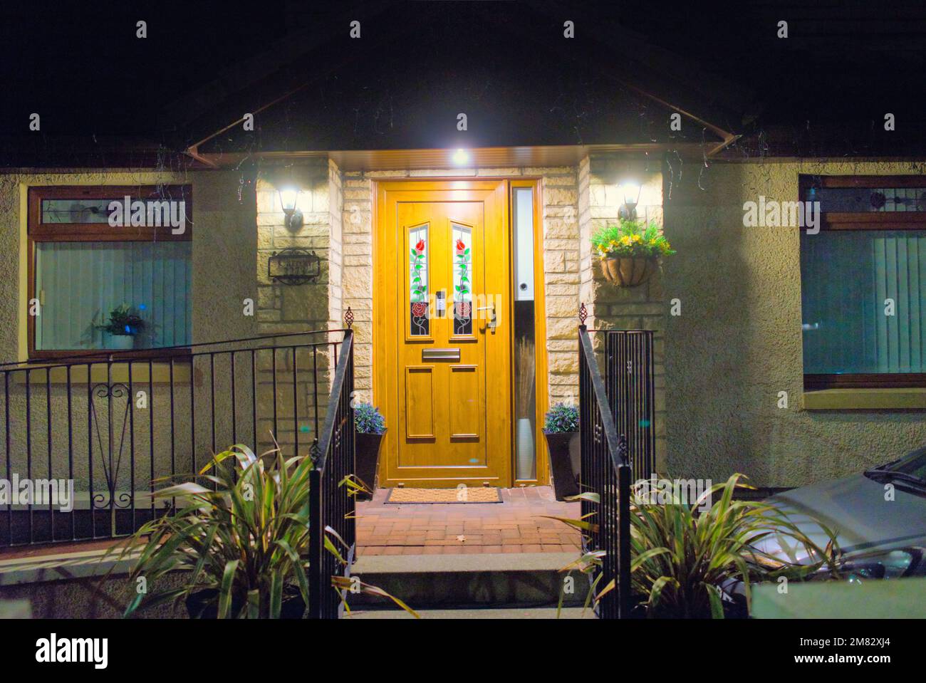 el porche de la puerta principal de los suburbios de clase media se iluminaba por la noche Foto de stock