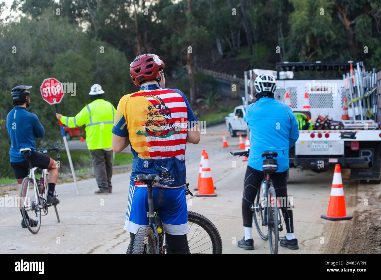 promoción Inspiración Sentido táctil Santa Bárbara, California, EE.UU. 12th de enero de 2023. Un ciclista con  una camisa de rayas rojas, blancas y azules con una serpiente en ella  espera mientras los trabajadores de servicios públicos