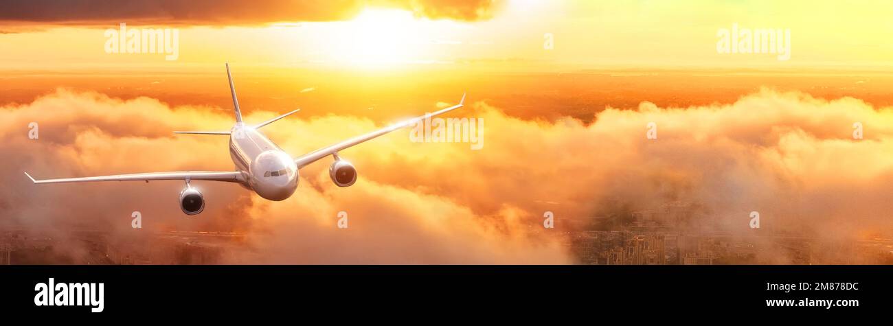 Avión volador de avión civil comercial sobre las nubes durante el amanecer del atardecer Luz reflejada brillante realista retroiluminada, amplia vista de la bandera Foto de stock