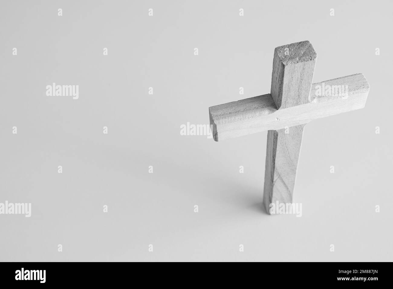 Simple cruz cristiana de madera de pie sobre un fondo blanco tomado desde arriba con espacio de copia Foto de stock