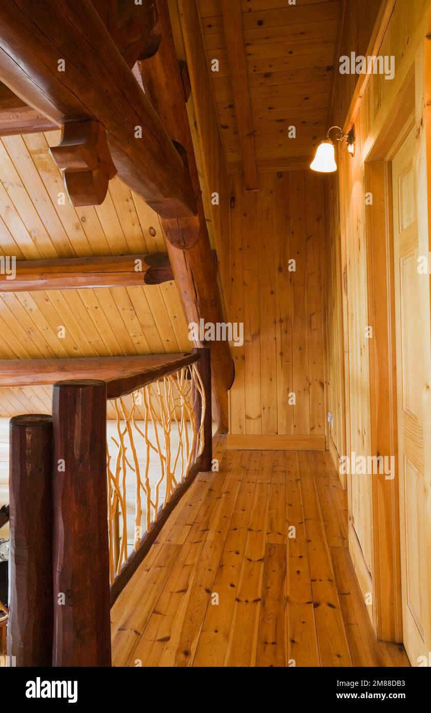 Barandilla de rama de cedro y suelos de madera de pino rojo en el piso de arriba dentro de la casa de madera de estilo escandinavo. Foto de stock