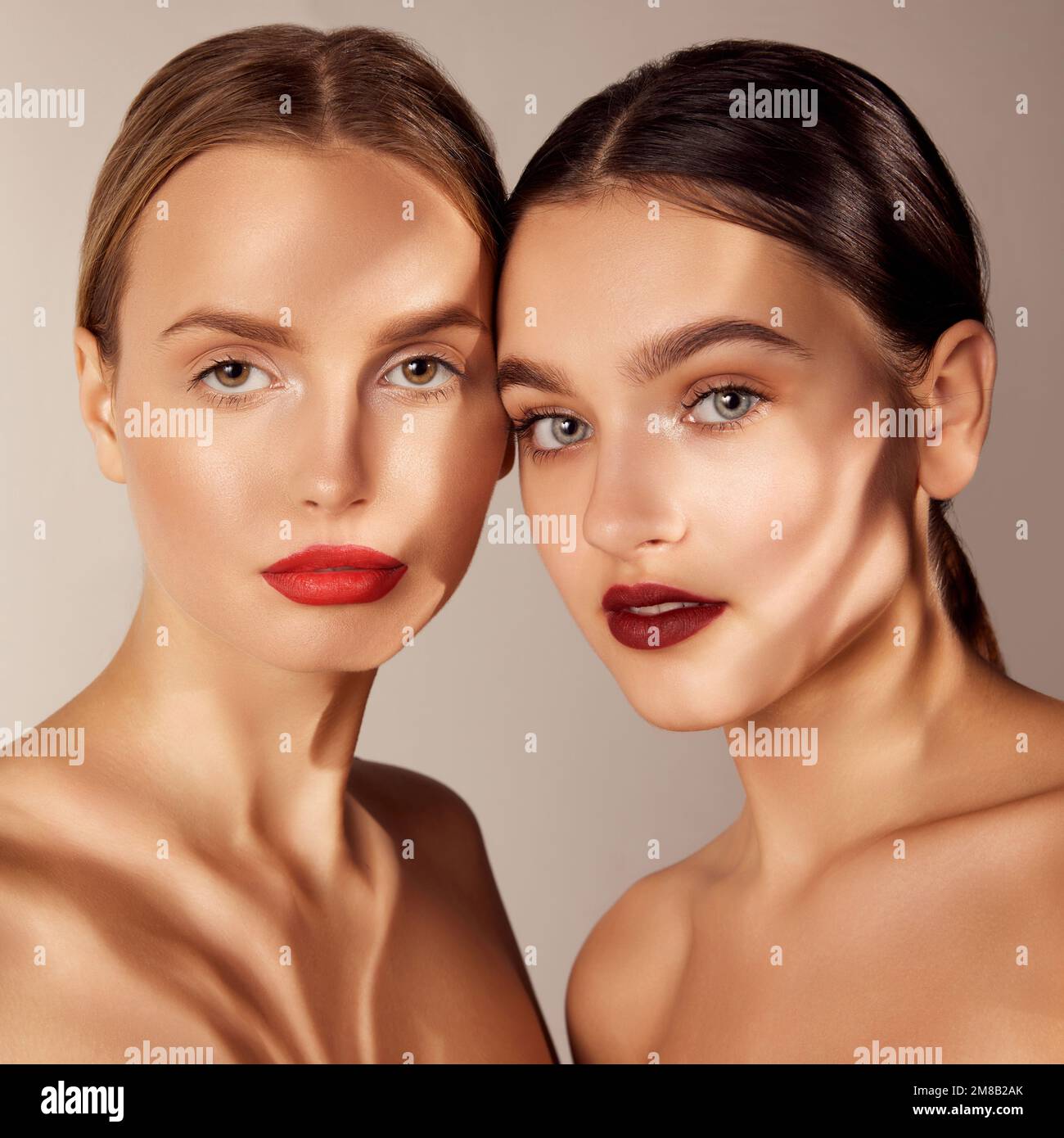 Tierna juventud. Retrato de dos muchachas jóvenes, hermosas con maquillaje  de labios rojos aislados sobre fondo gris del estudio. Sombras. Concepto de  cuidado de la piel Fotografía de stock - Alamy