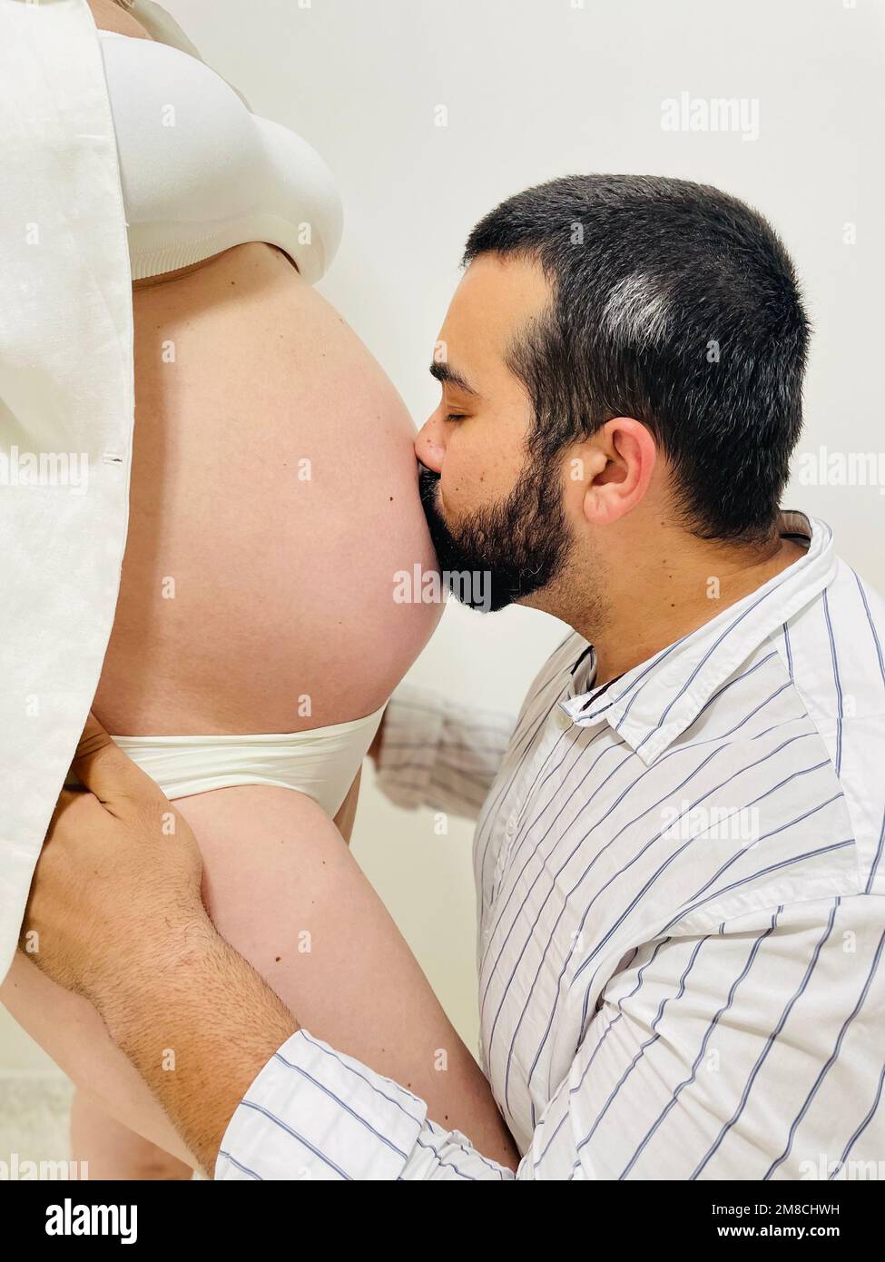 Besando el vientre de una mujer embarazada Foto de stock