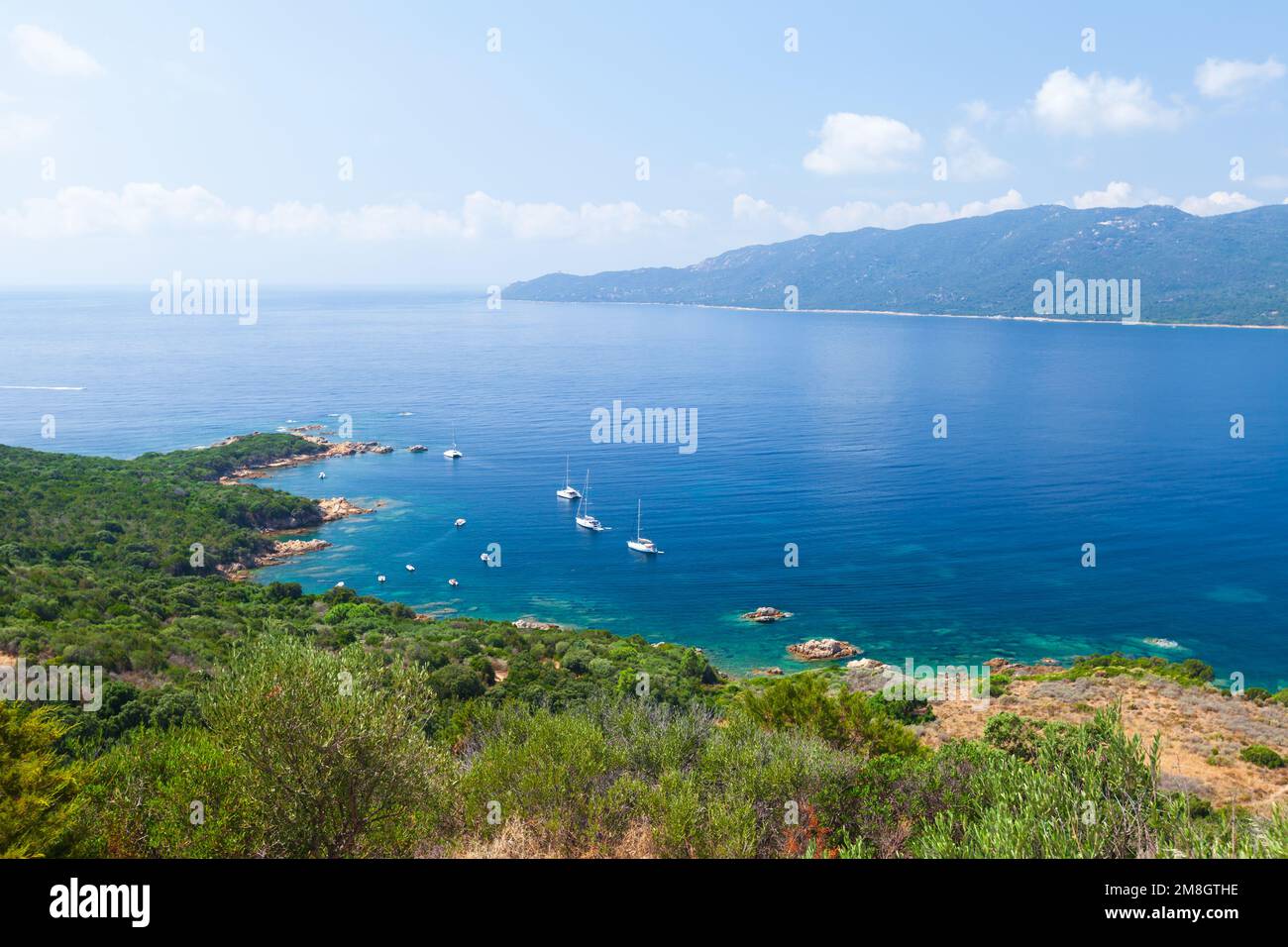 Isla Córcega en un día soleado, golfo Cupabia. Paisaje de verano con barcos de recreo anclados cerca de la costa rocosa Foto de stock