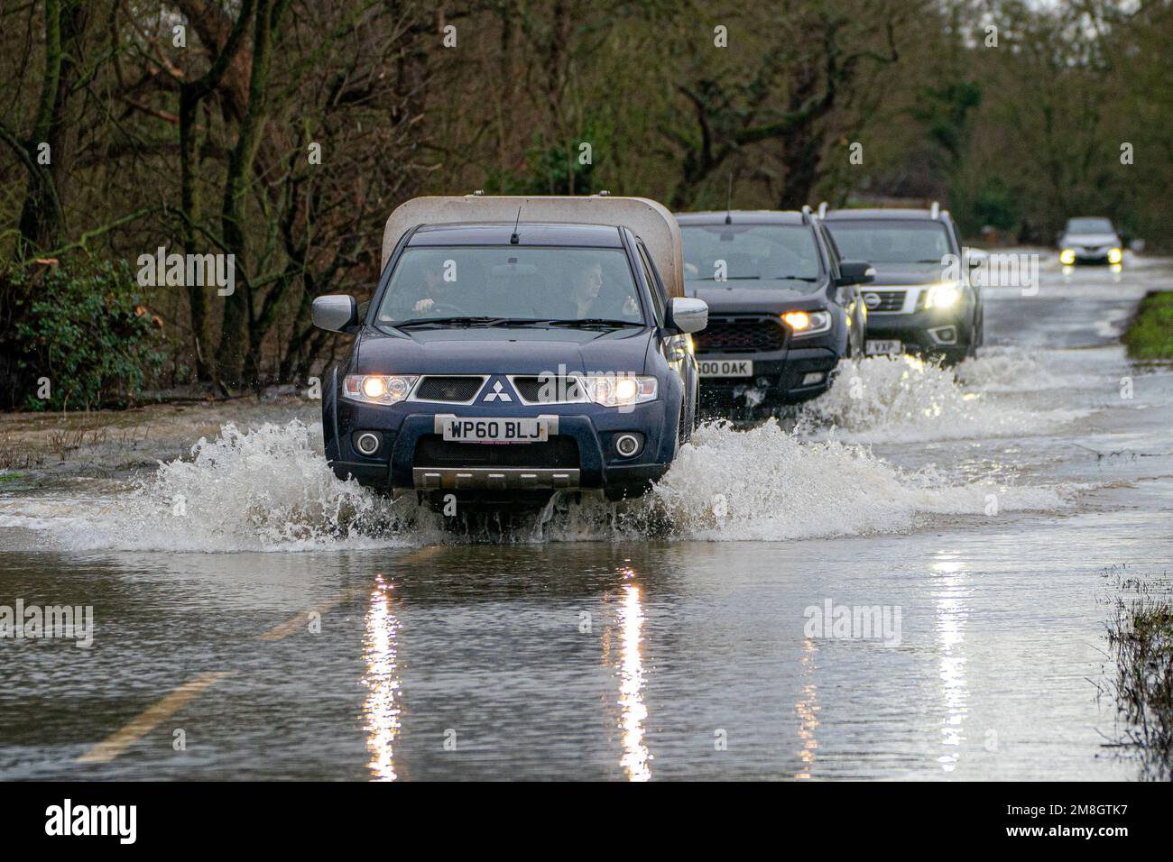 Los vehículos son conducidos a través de las inundaciones en Apperley, Gloucestershire, donde el río Severn irrumpió en sus orillas y ha inundado campos y carreteras en todo el condado. Las fuertes lluvias y los vientos azules en gran parte del Reino Unido este fin de semana serán seguidos por un período de clima frío potencialmente severo la próxima semana. Fecha de la foto: Sábado 14 de enero de 2023. Foto de stock