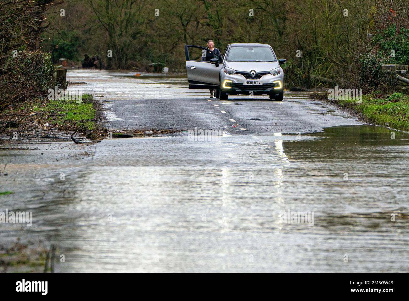 Un conductor se detiene para revisar el vehículo después de conducir a través de las inundaciones en Apperley, Gloucestershire, donde el río Severn estalló en sus orillas y ha inundado campos y carreteras en todo el condado. Las fuertes lluvias y los vientos azules en gran parte del Reino Unido este fin de semana serán seguidos por un período de clima frío potencialmente severo la próxima semana. Fecha de la foto: Sábado 14 de enero de 2023. Foto de stock