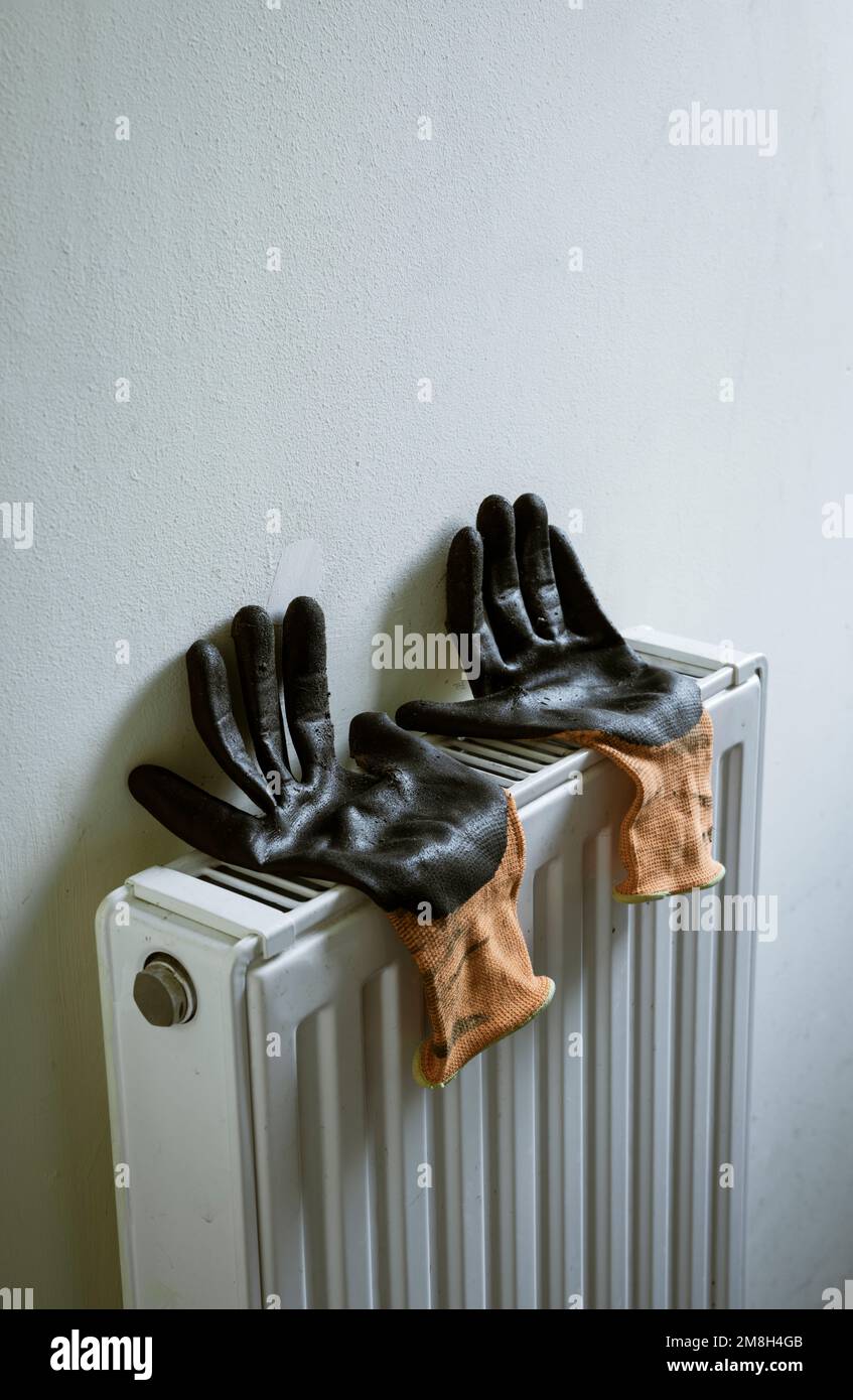 Guantes de trabajo que se secan en un radiador. Foto de stock