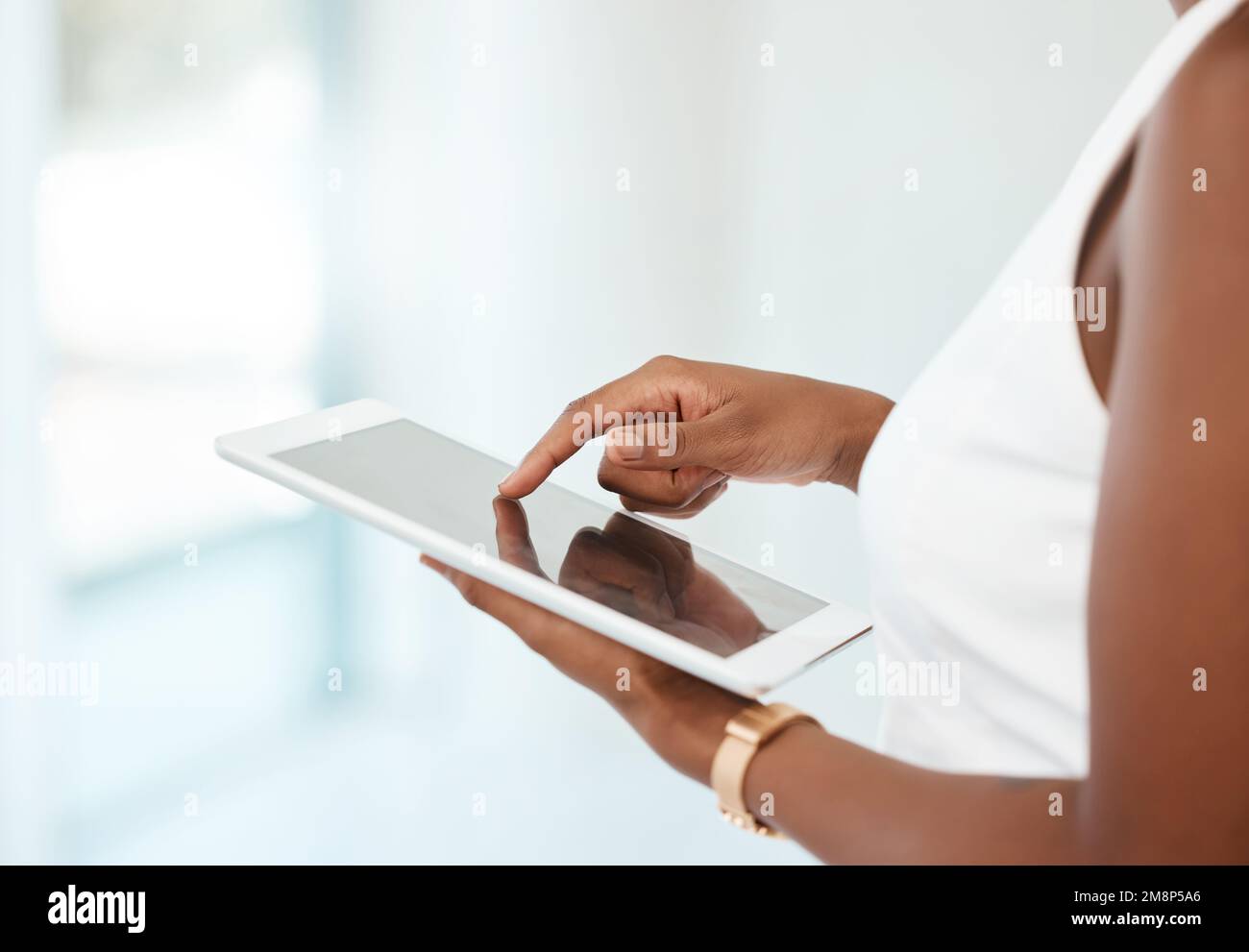 Persona irreconocible sosteniendo y usando una tableta digital en casa. Mujer irreconocible usando las redes sociales en una tableta digital sola en el trabajo Foto de stock