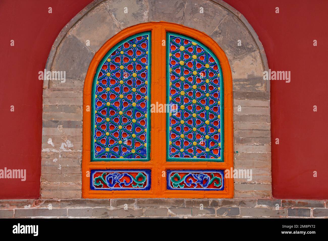 Fachada roja y ventana simétrica pintada de colores en la Casa de los Sacerdotes en el Monasterio Tibetano Kumbum, Xining, China Foto de stock