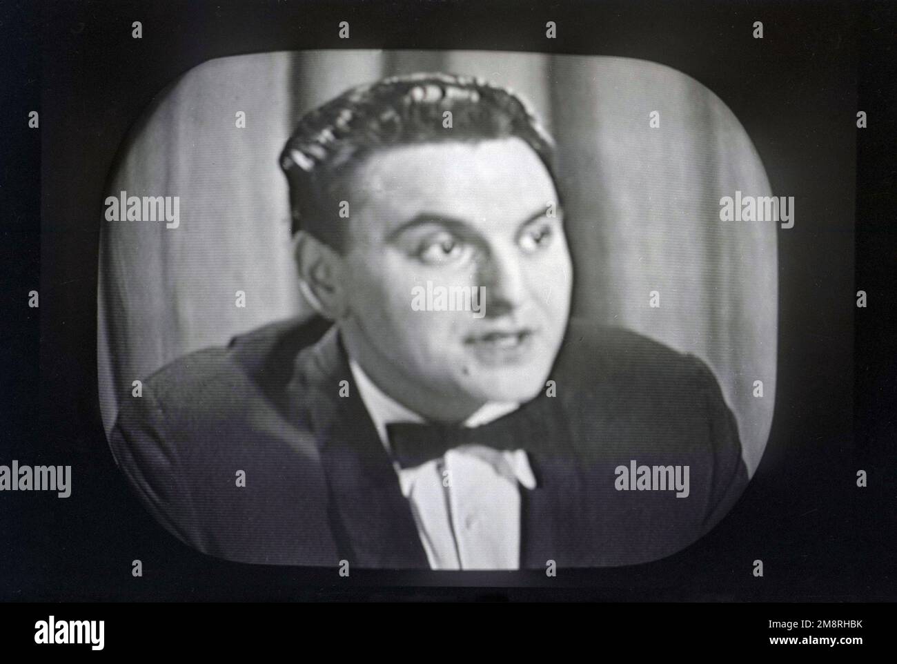 1957, histórico, actor y comediante Bob Monkhouse en BBC Television, Inglaterra, Reino Unido. Aparece en el programa de juegos británico, What's My Line?. Transmitido en BBC Television desde 1951 hasta 1963, el programa de juegos de panel se basó en la versión estadounidense del mismo nombre, y fue uno de los programas de televisión más populares de la época. Los panelistas del programa tuvieron que interrogar a los concursantes para tratar de adivinar su ocupación, es decir, su 'línea de trabajo'. Foto de stock