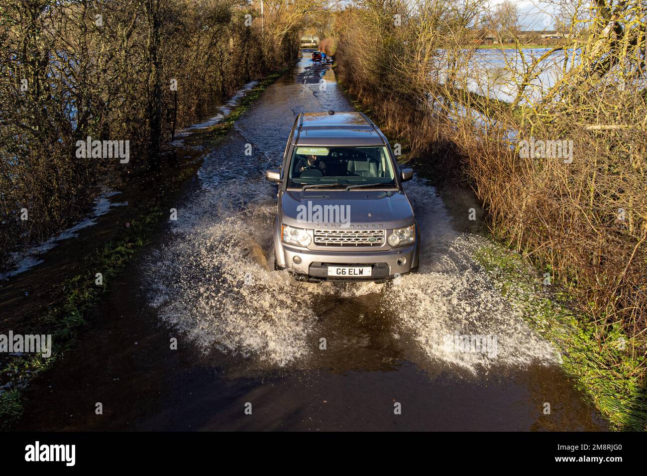 Un coche conduce a través de las inundaciones cerca de Muchelney, Somerset. Fecha de la fotografía: Domingo 15 de enero de 2023. Foto de stock
