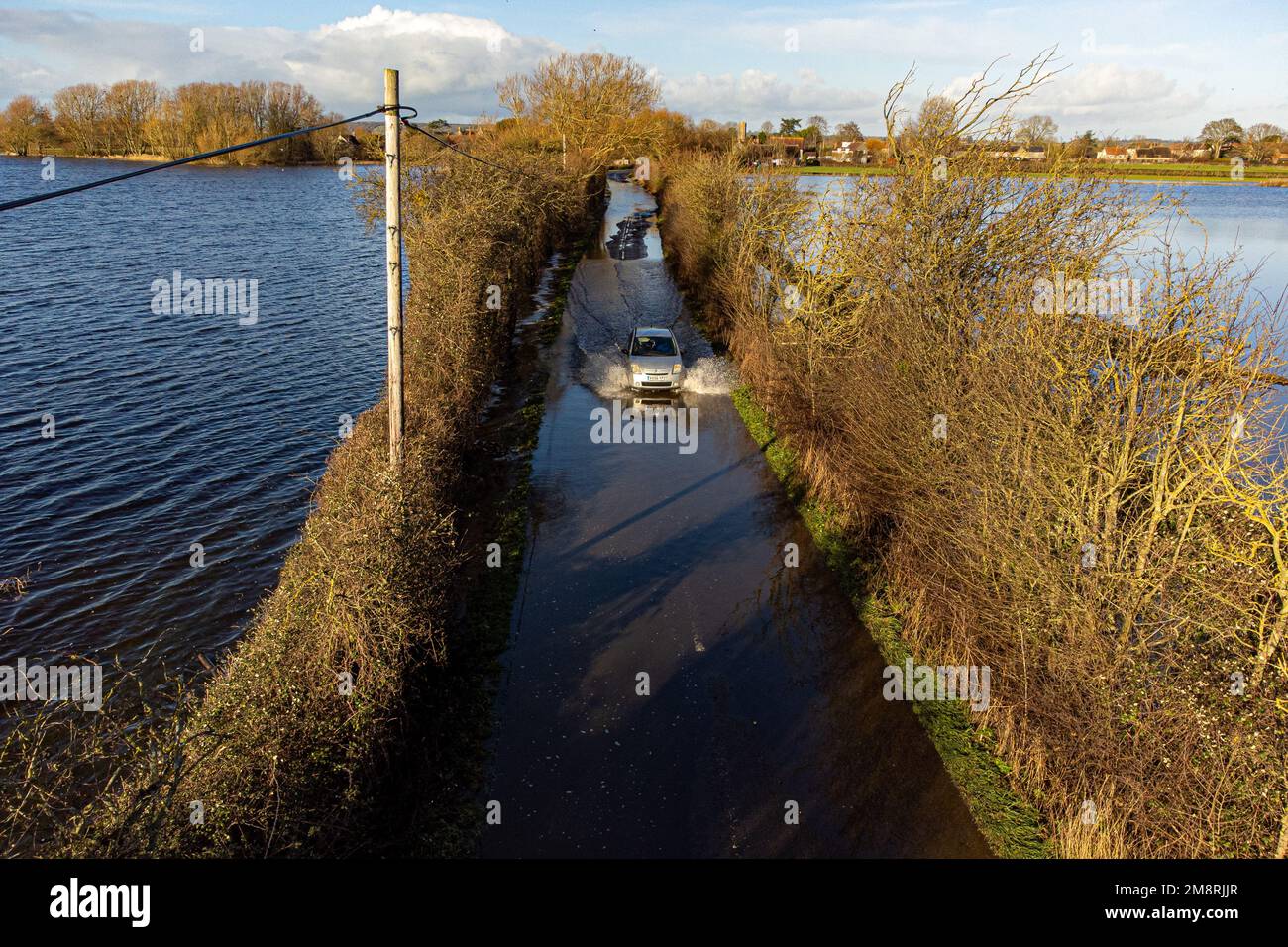 Un coche conduce a través de las inundaciones cerca de Muchelney, Somerset. Fecha de la fotografía: Domingo 15 de enero de 2023. Foto de stock