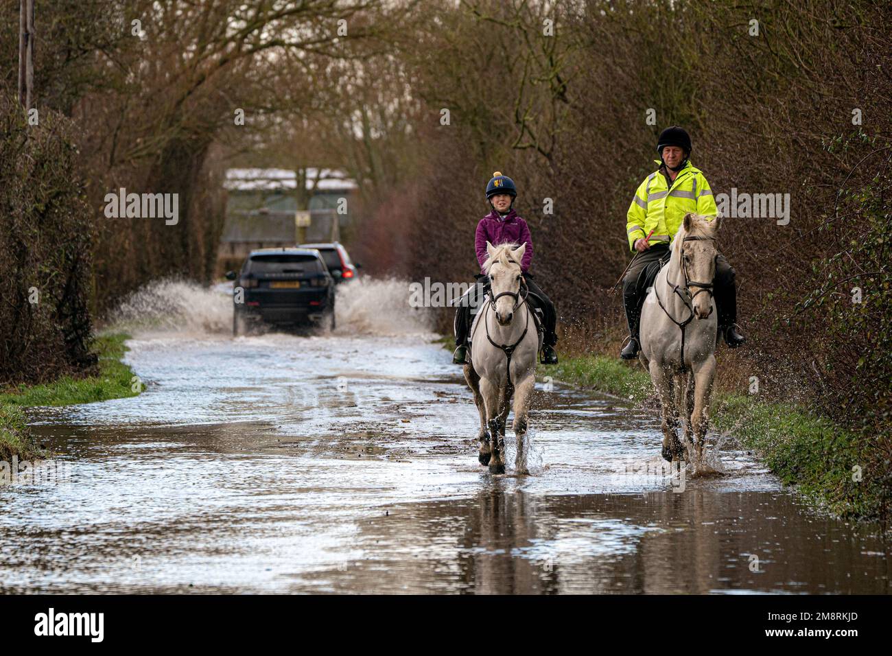 Caballos y jinetes hacen su camino a través de las inundaciones cerca de Muchelney, Somerset. Fecha de la fotografía: Domingo 15 de enero de 2023. Foto de stock