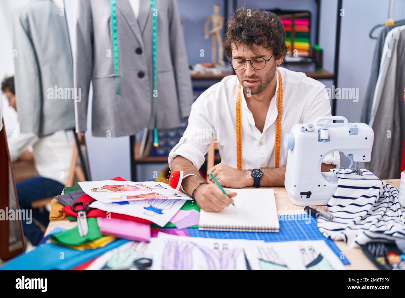 Joven hombre hispano sastre dibujo en cuaderno en la fábrica de ropa  Fotografía de stock - Alamy