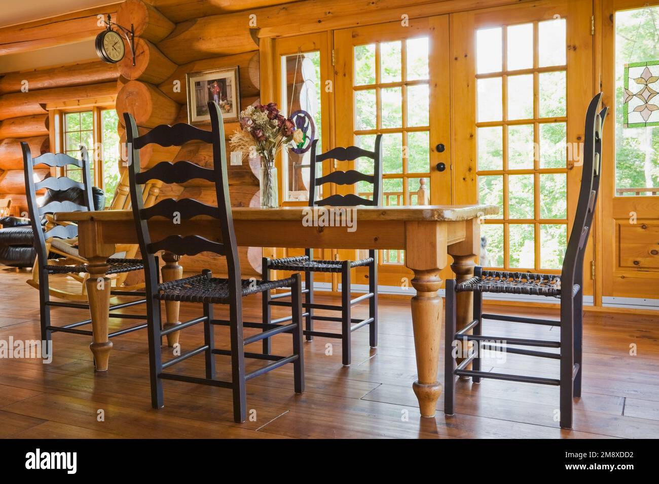 Mesa de comedor de madera de pino con sillas de asiento de cuero de rastrillo tejidas de respaldo alto en el comedor dentro de la casa de madera de estilo escandinavo. Foto de stock