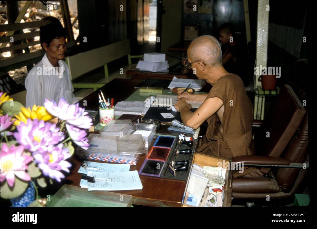 Un monje registra a un nuevo recluso que ha venido a Wat Tham Krabok, monasterio de rehabilitación de drogas en Tailandia, 1988 Foto de stock
