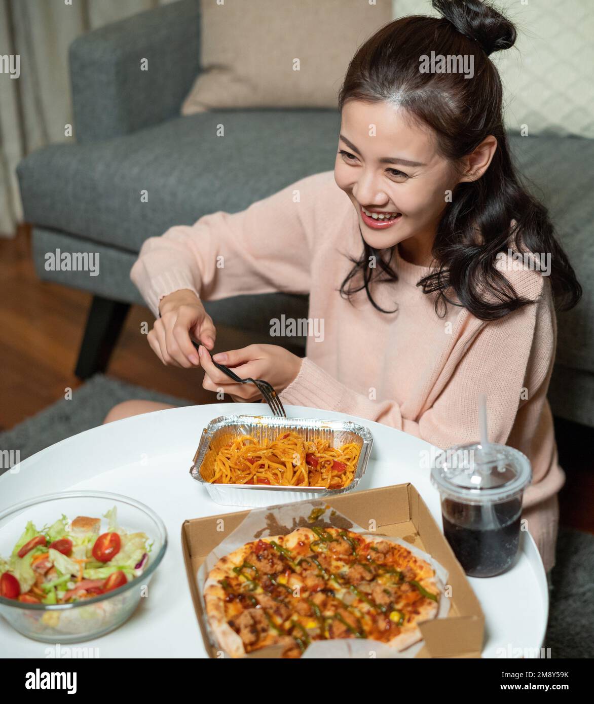 La joven en casa comiendo comida para llevar Foto de stock