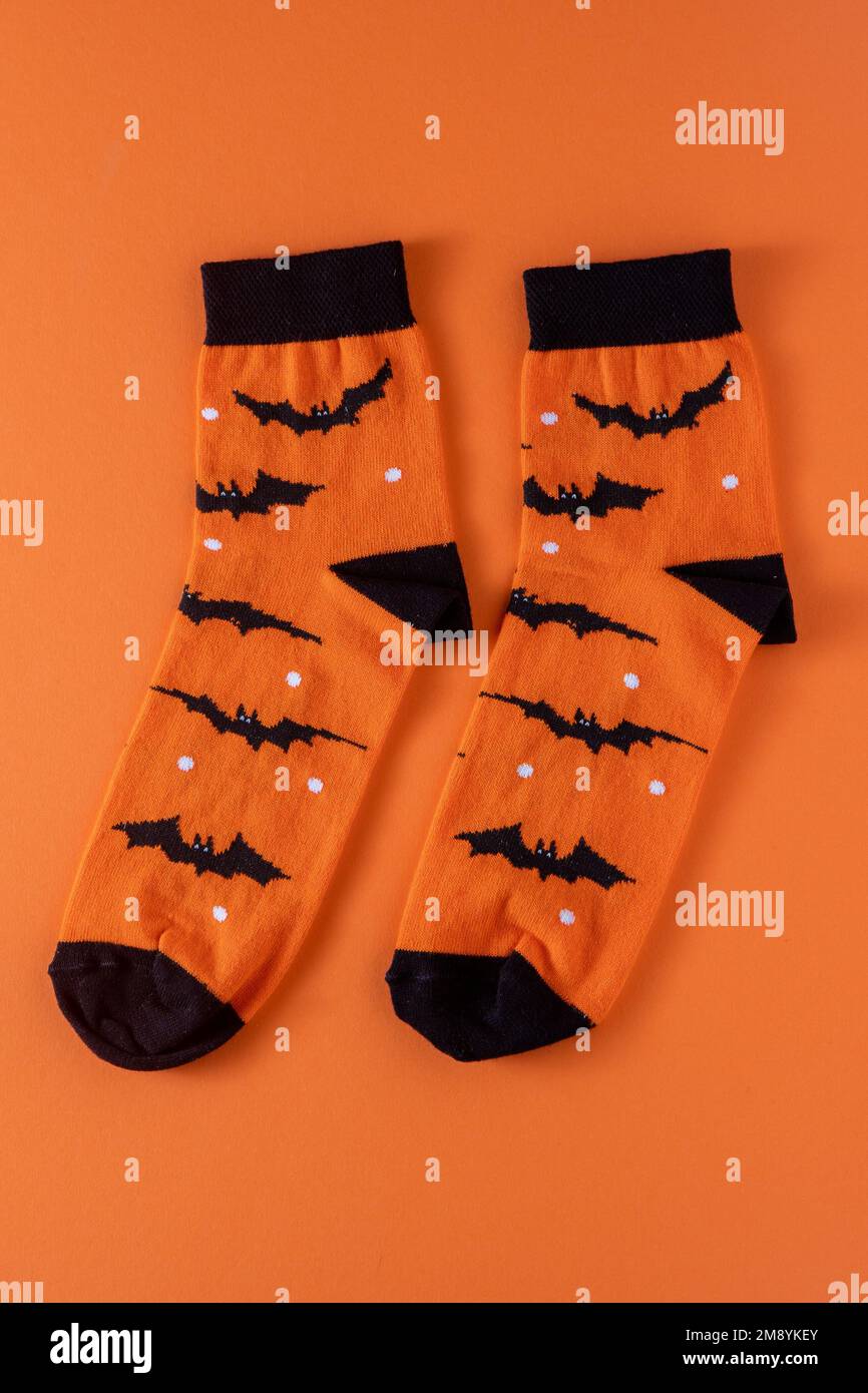 Calcetines naranjas con murciélagos. Disfraz de ropa para fiesta de Halloween. Vista superior del calcetín multicolor brillante y alegre. Foto de stock