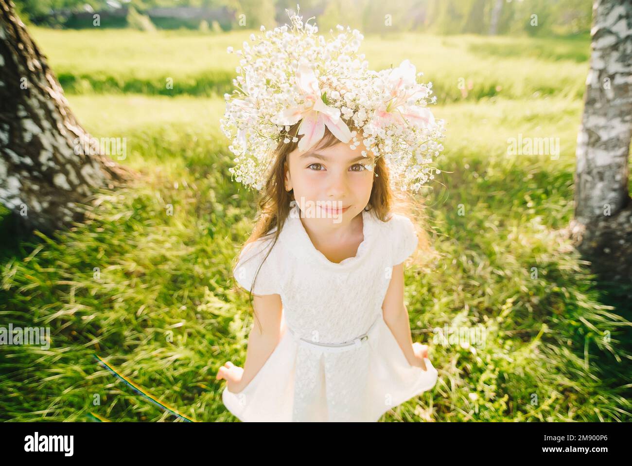 Muchacha joven feliz con una guirnalda de flores en su cabeza Apariencia caucásica sonriendo en el verano al aire libre Foto de stock