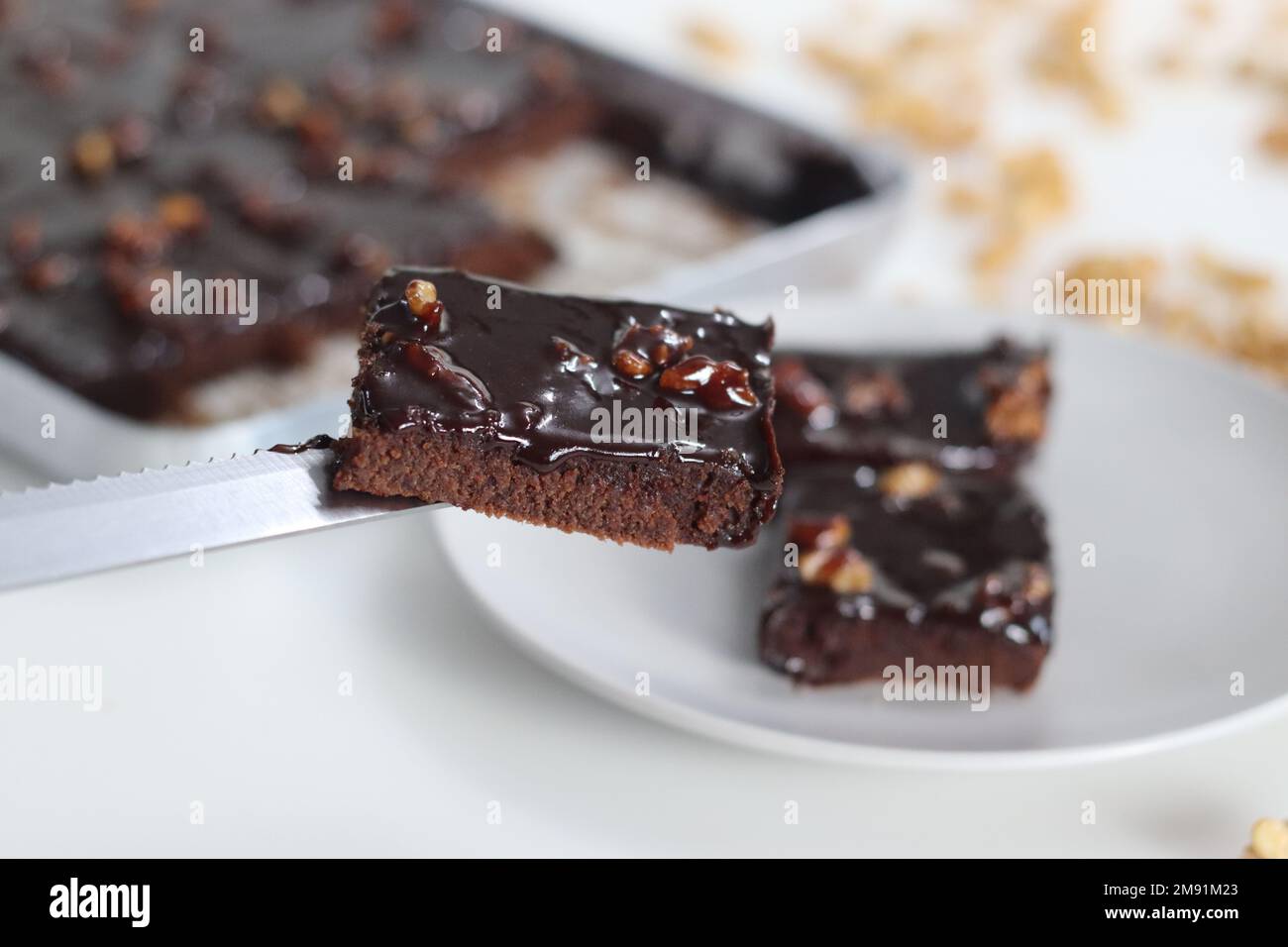 Rebanada de Texas Sheet Cake servida en un plato. Es un pastel de chocolate grande y delgado cubierto con un rico glaseado de nueces de chocolate. Es húmedo y esponjoso, w Foto de stock