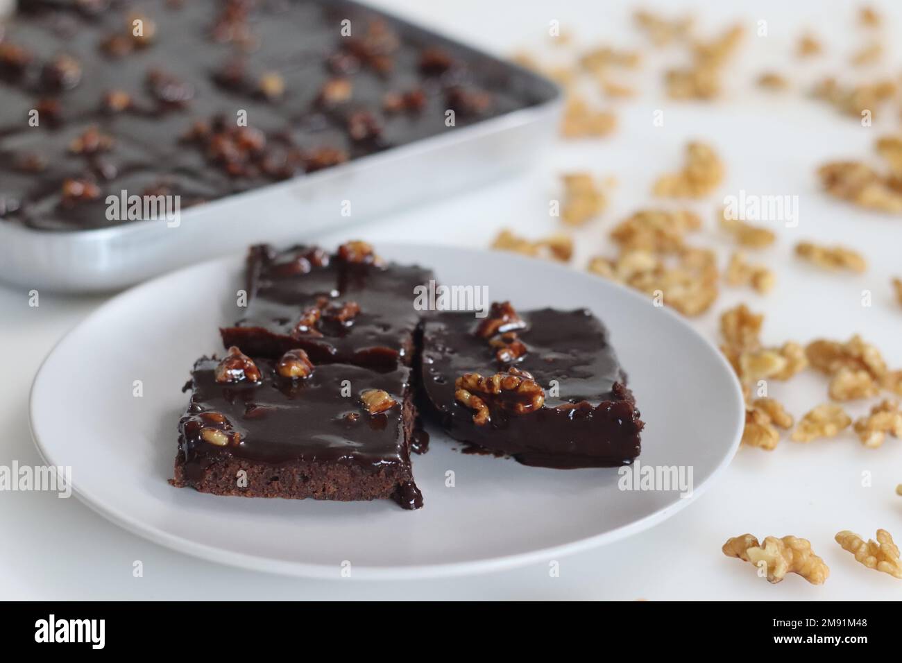 Rebanada de Texas Sheet Cake servida en un plato. Es un pastel de chocolate grande y delgado cubierto con un rico glaseado de nueces de chocolate. Es húmedo y esponjoso, w Foto de stock